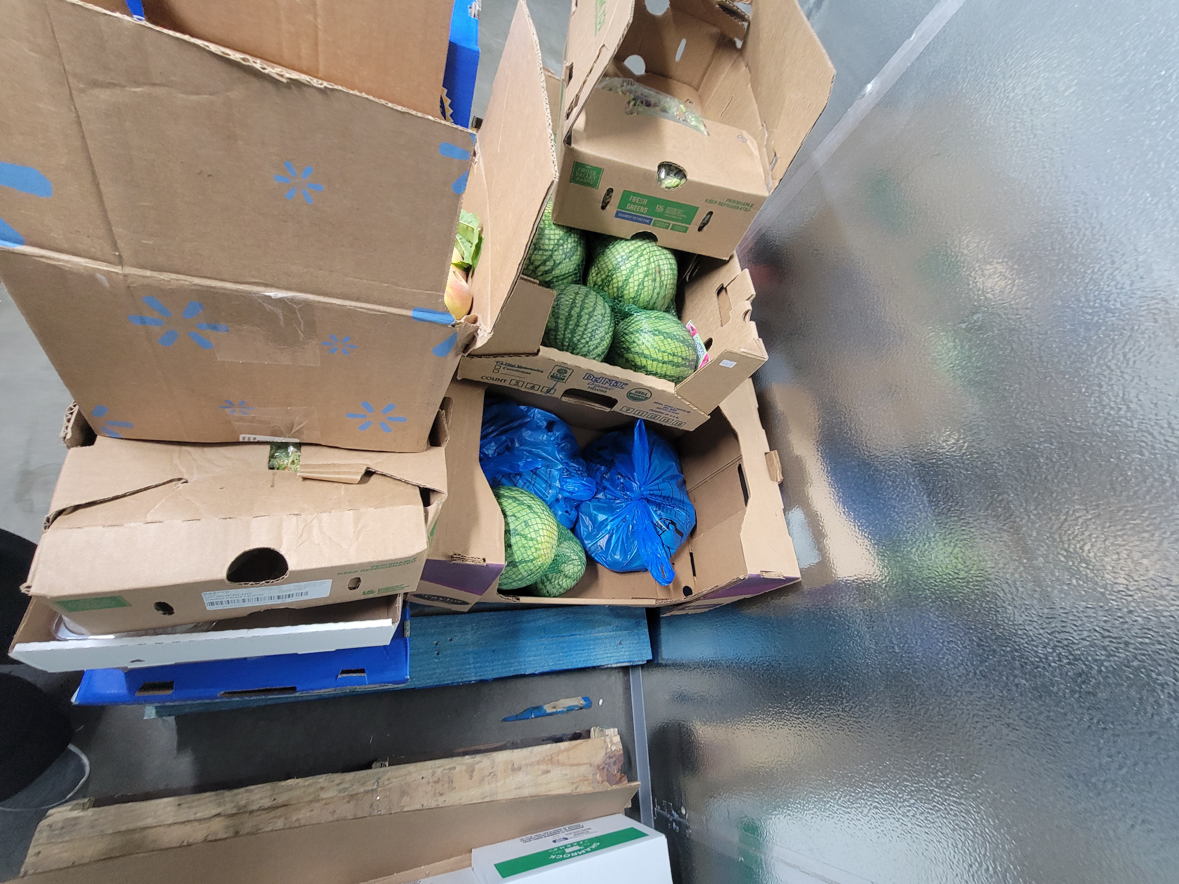 Cardboard boxes with blue bags and watermelons filled in two.